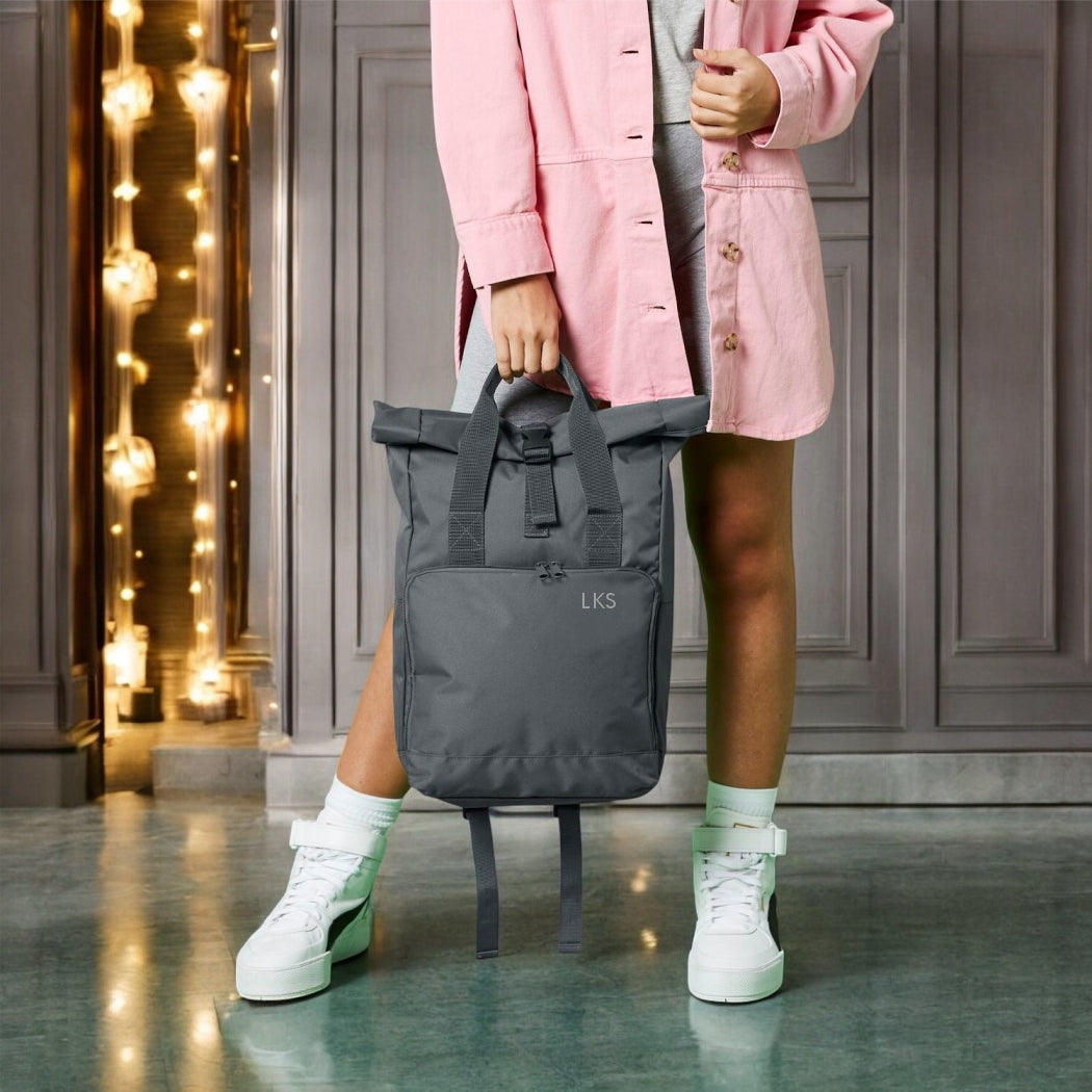 Person holding a grey backpack with 'LKS' branding in a decorative indoor setting.
