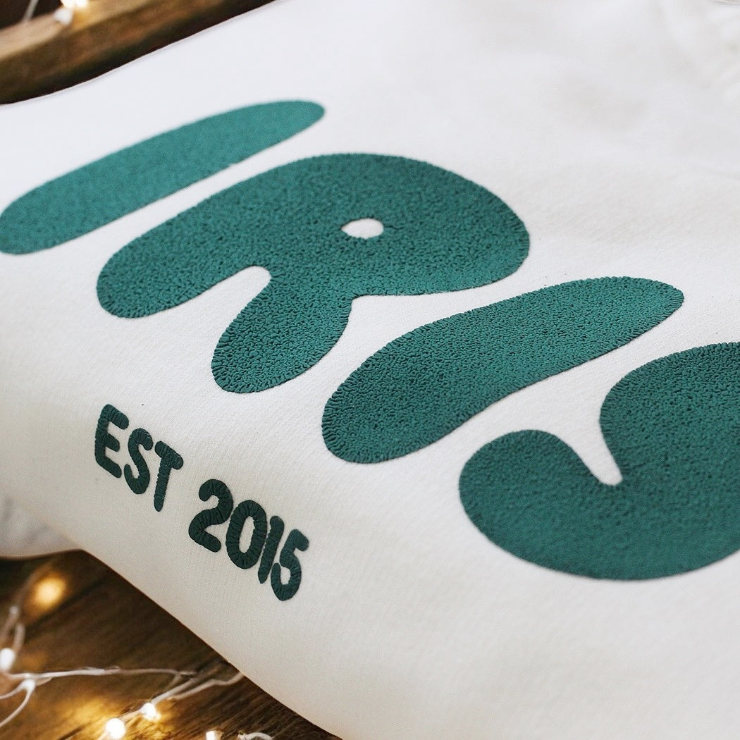 White puff with green design and 'EST 2016' text on a wooden surface.
