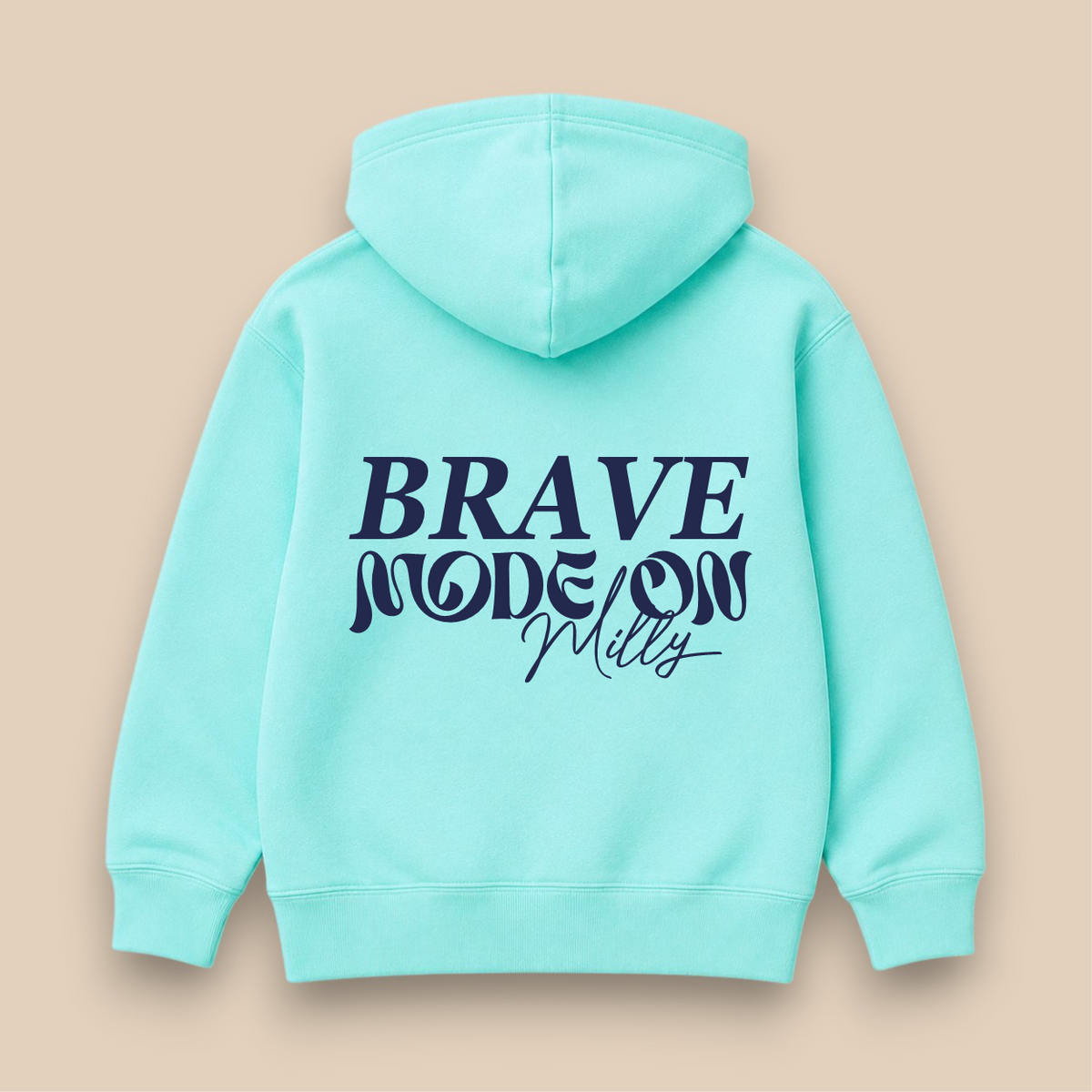 A mint green hoodie shown from the back, featuring the text 'BRAVE MODE ON' printed in dark navy blue. The hoodie is displayed flat against a solid beige background.