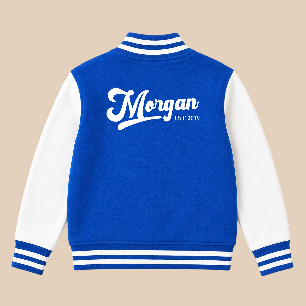 A blue and white varsity-style jacket shown from the back, with white sleeves, striped ribbed collar/cuffs/hem, and a large white script reading 'Morgan EST 2019' across the upper back, on a beige background.