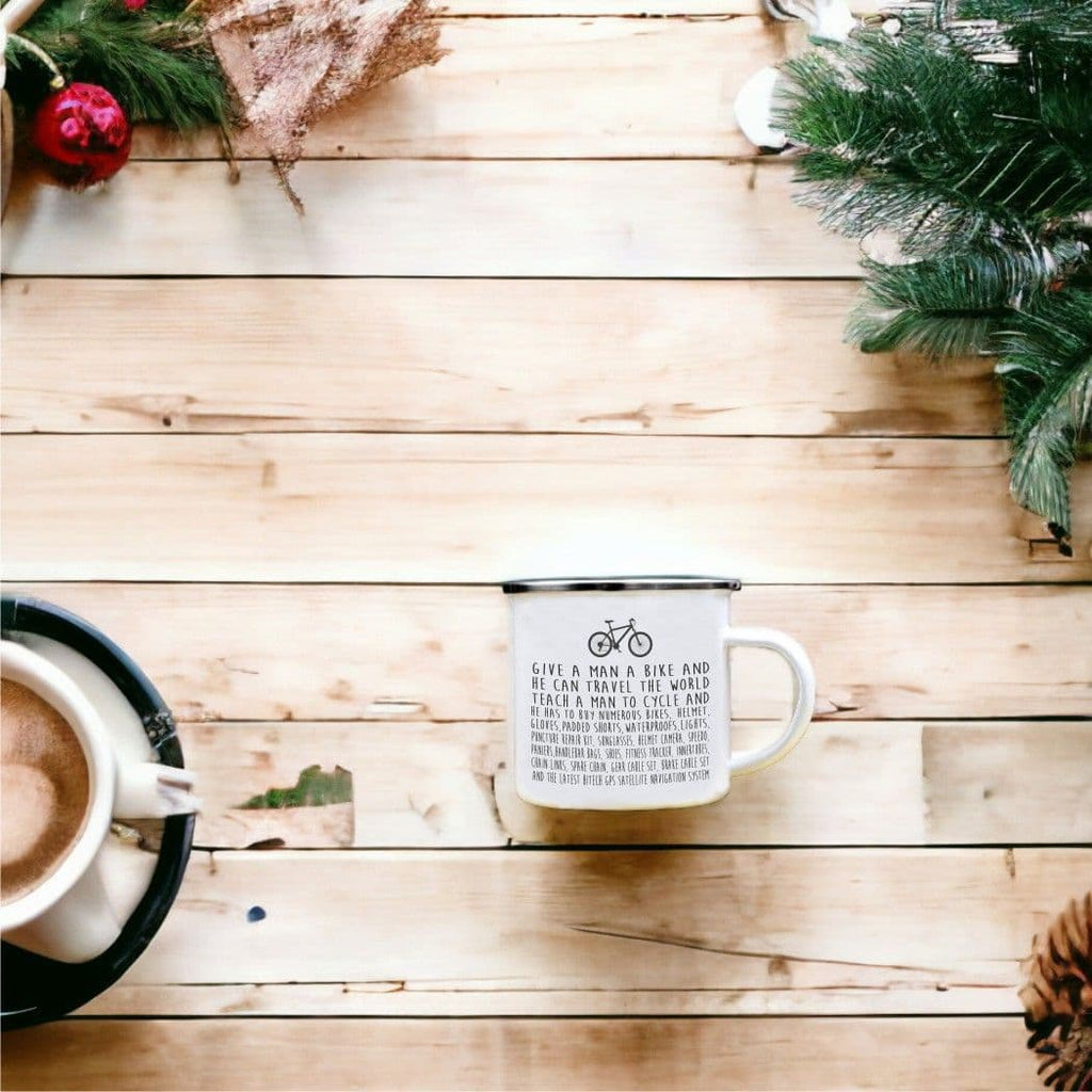 White mug with text on a wooden surface with a Christmas tree and decorations.