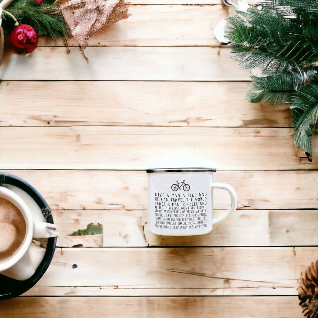 White mug with text on a wooden surface with a Christmas tree and decorations.