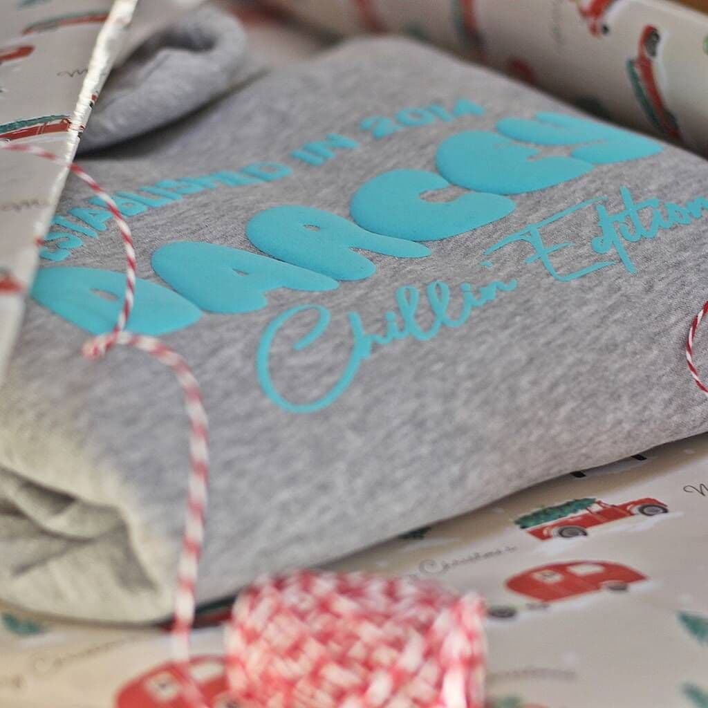 Gray sweatshirt with turquoise text on a patterned surface