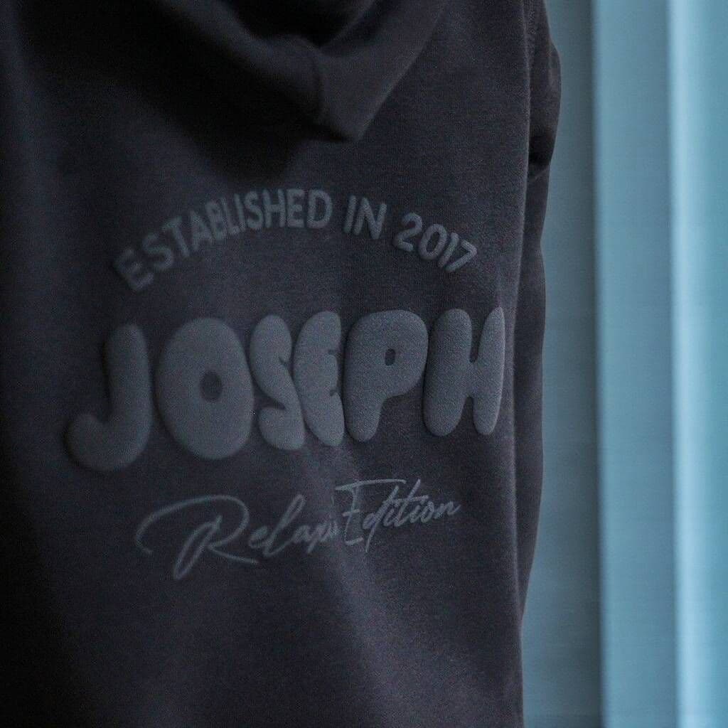 Dark gray hoodie with 'JOSEPH' branding and text on a blurred background