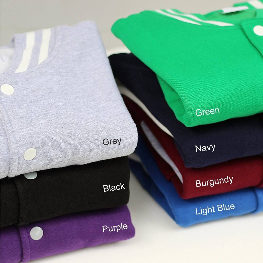 Stack of folded varsity jackets in various colors with labels on a white background