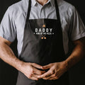 Person wearing a black apron with 'Daddy King of the Pizza' text