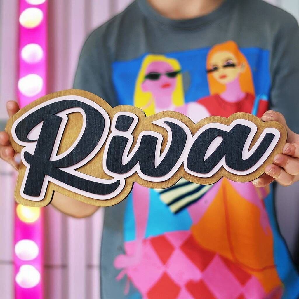 Person holding a sign with 'Riva' in front of a colorful background