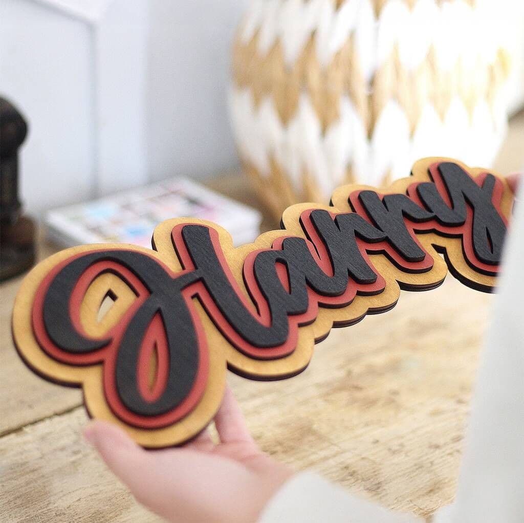 Decorative sign with 'Harry' in black and burgundy red on a wooden surface