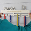 Person holding a netball-themed medal holder with ribbons against a light gray background