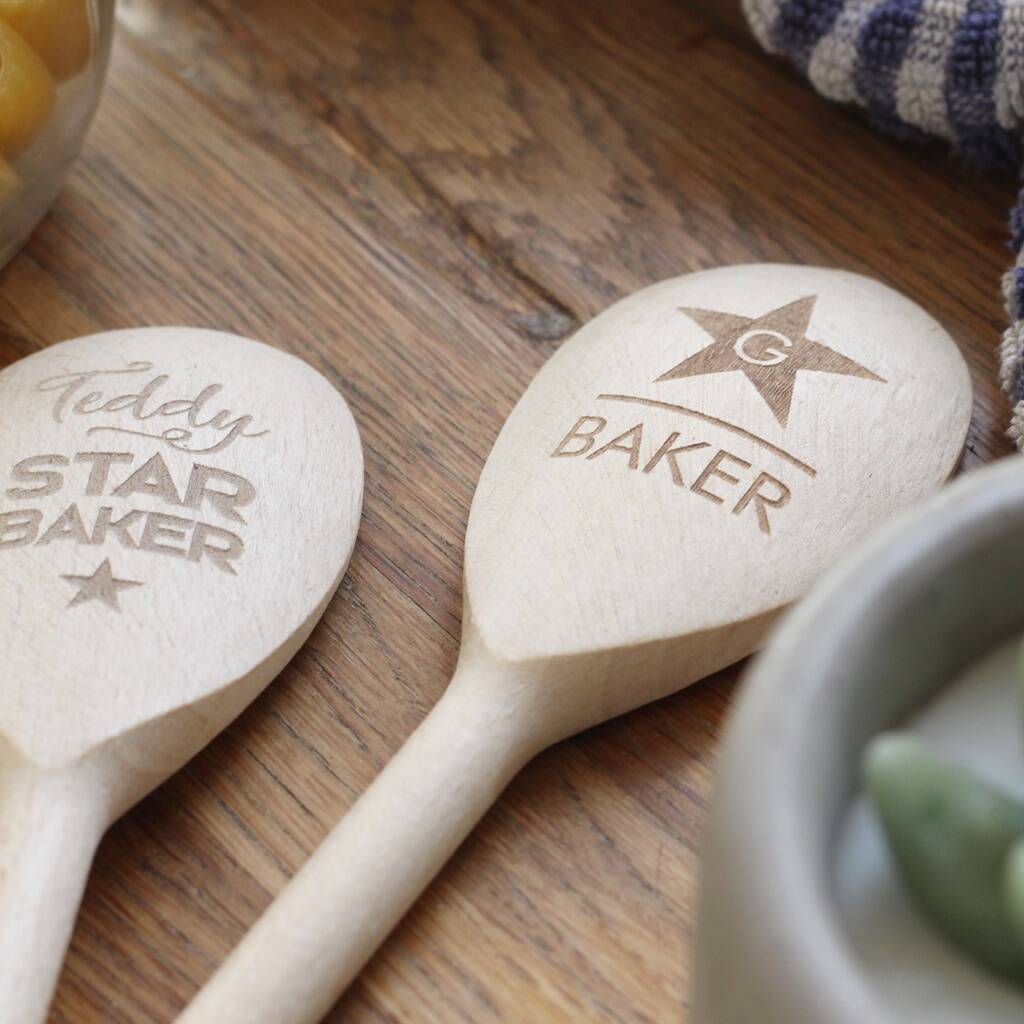 Two wooden spoons with engraved text on a wooden surface.