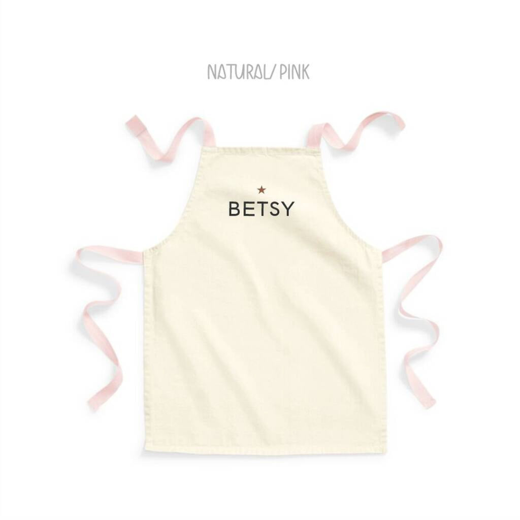 Light yellow apron with 'BETSY' text and pink straps on a white background