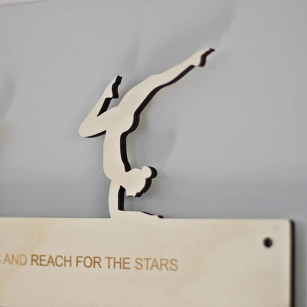 Wooden wall art of a leaping figure with 'REACH FOR THE STARS' text on a grey background