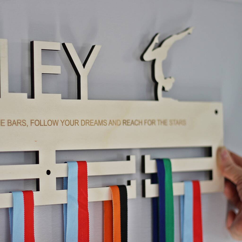 Medal holder with ribbons and motivational quote on a light grey background