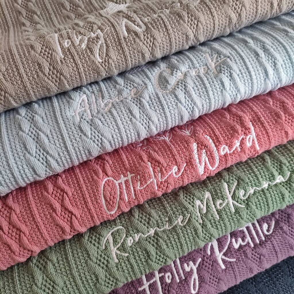 Stack of textured fabric swatches with embroidered names in various colors.