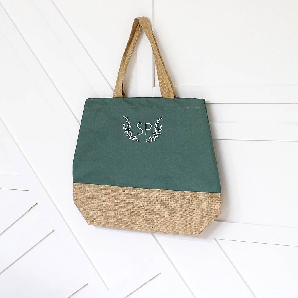 Green tote bag with beige bottom half and 'SP' logo on a white wooden floor