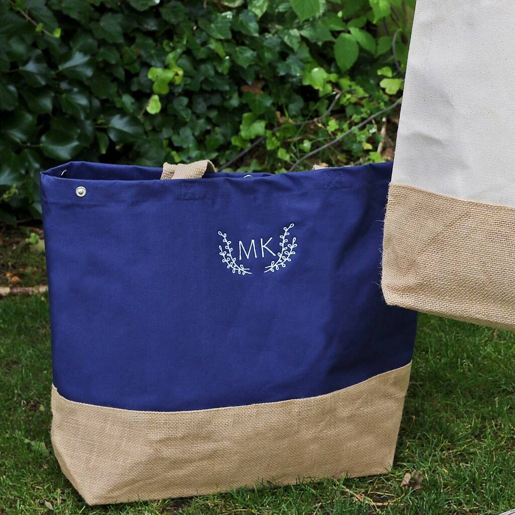 Blue tote bag with beige bottom section and 'MK' monogram on grass