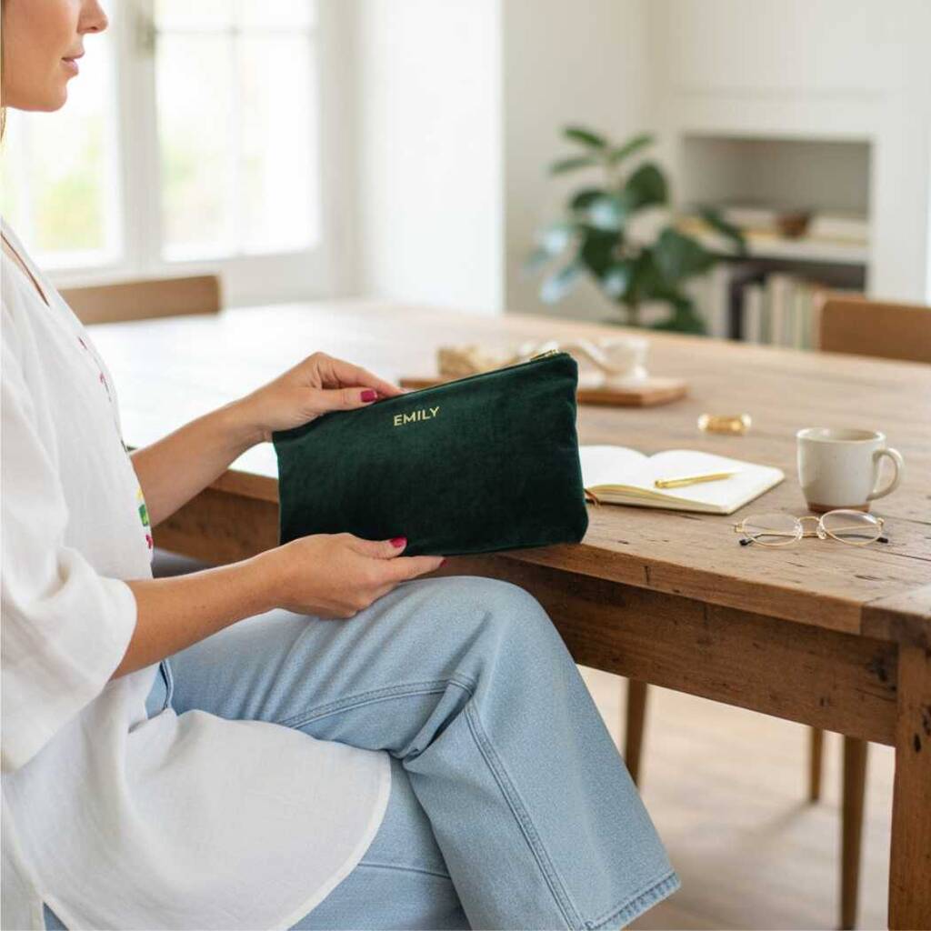 Person holding a green pouch with 'EMILY' on it in a home setting.