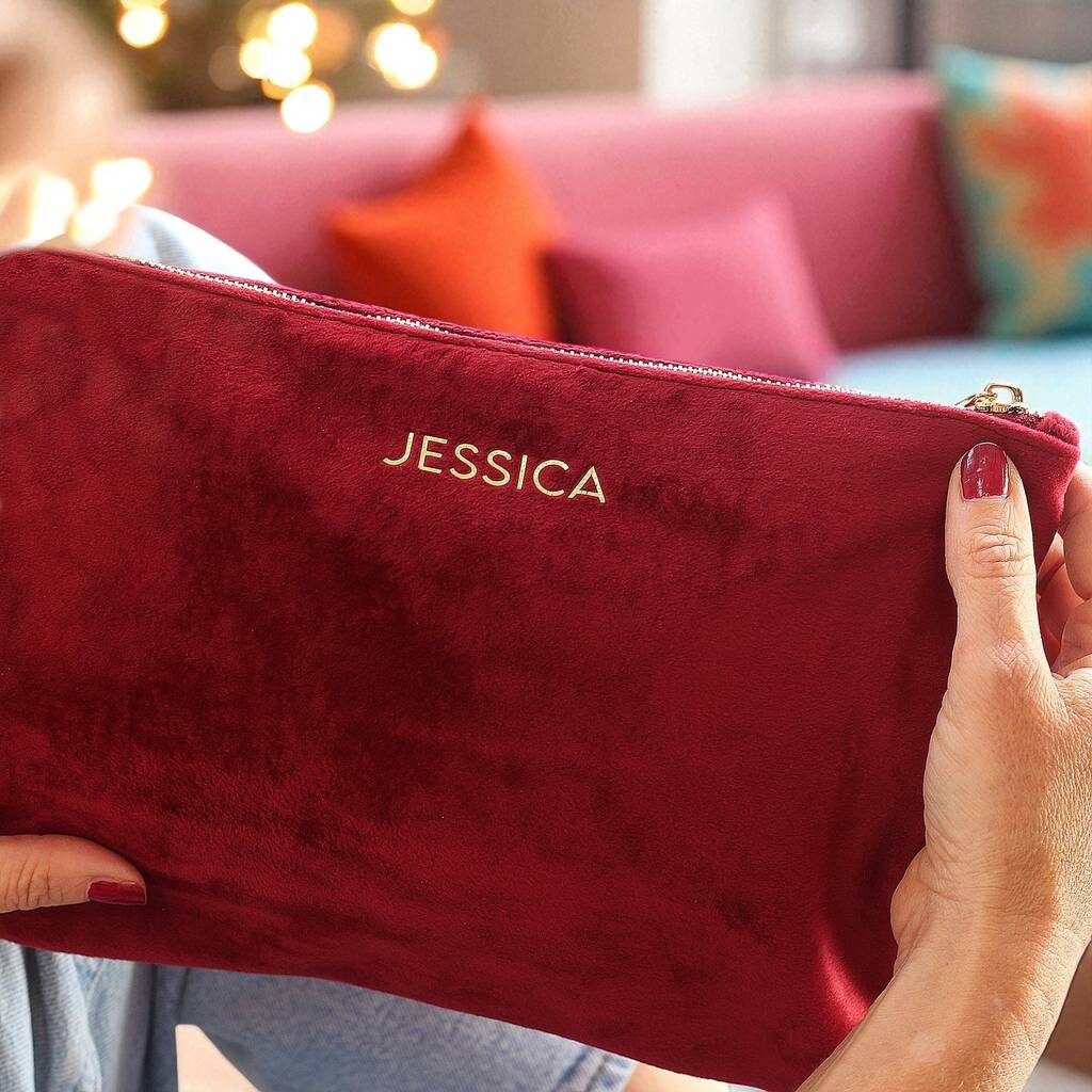 Red pouch with 'JESSICA' branding held by a person in a blurred indoor setting.