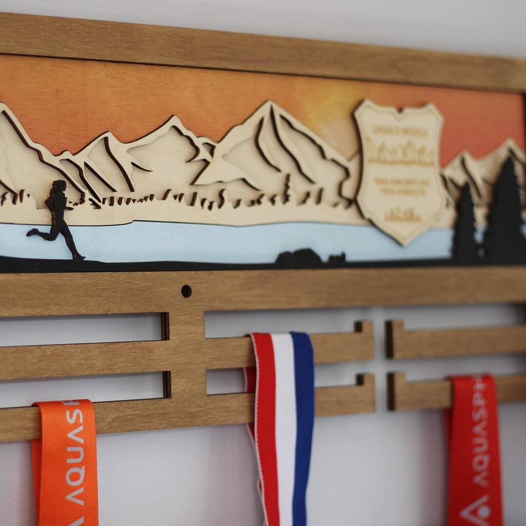 Wooden medal holder with mountain design and running silhouette, featuring Aquaspin ribbons.