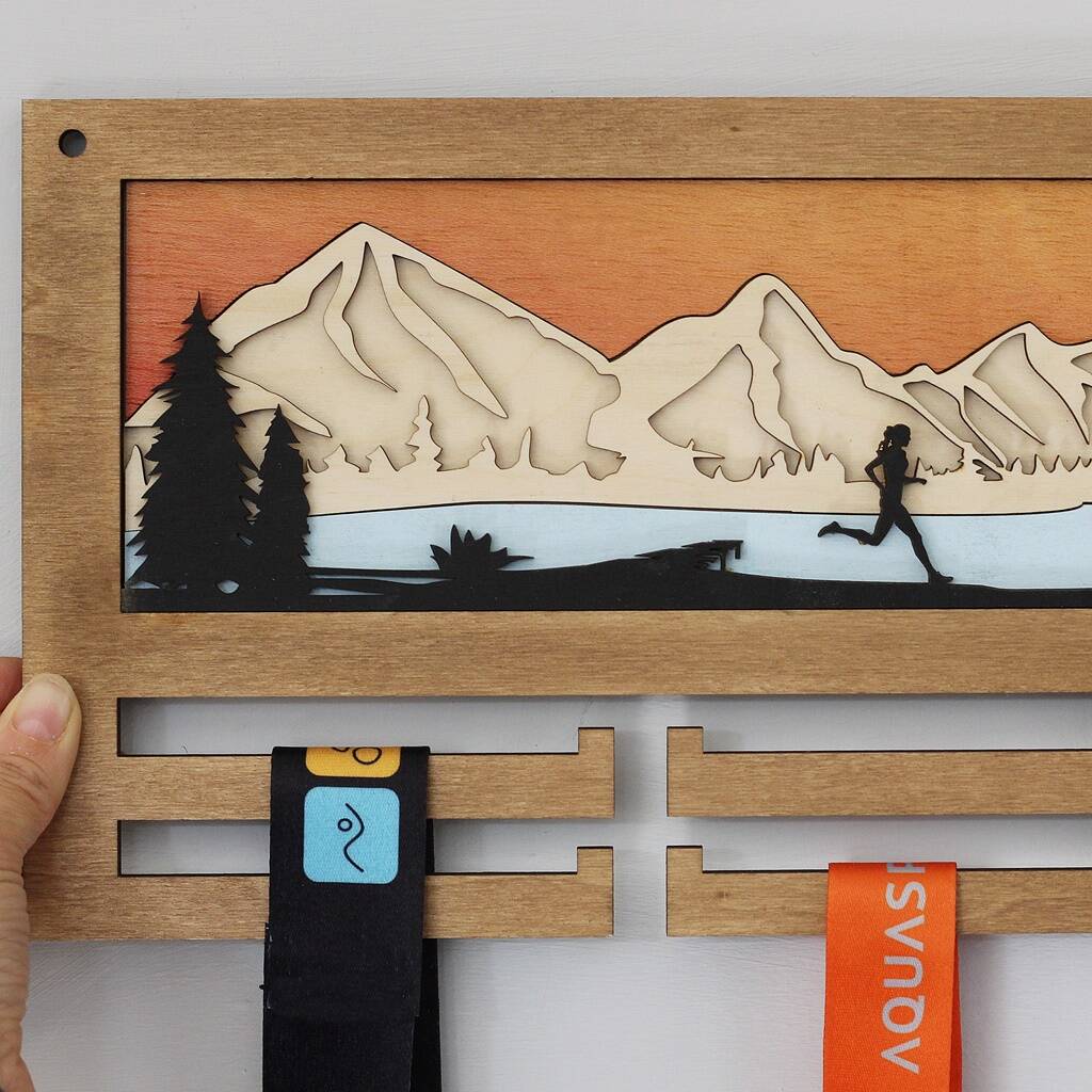 Wooden running medal hanger with mountain and running person design held by a hand.