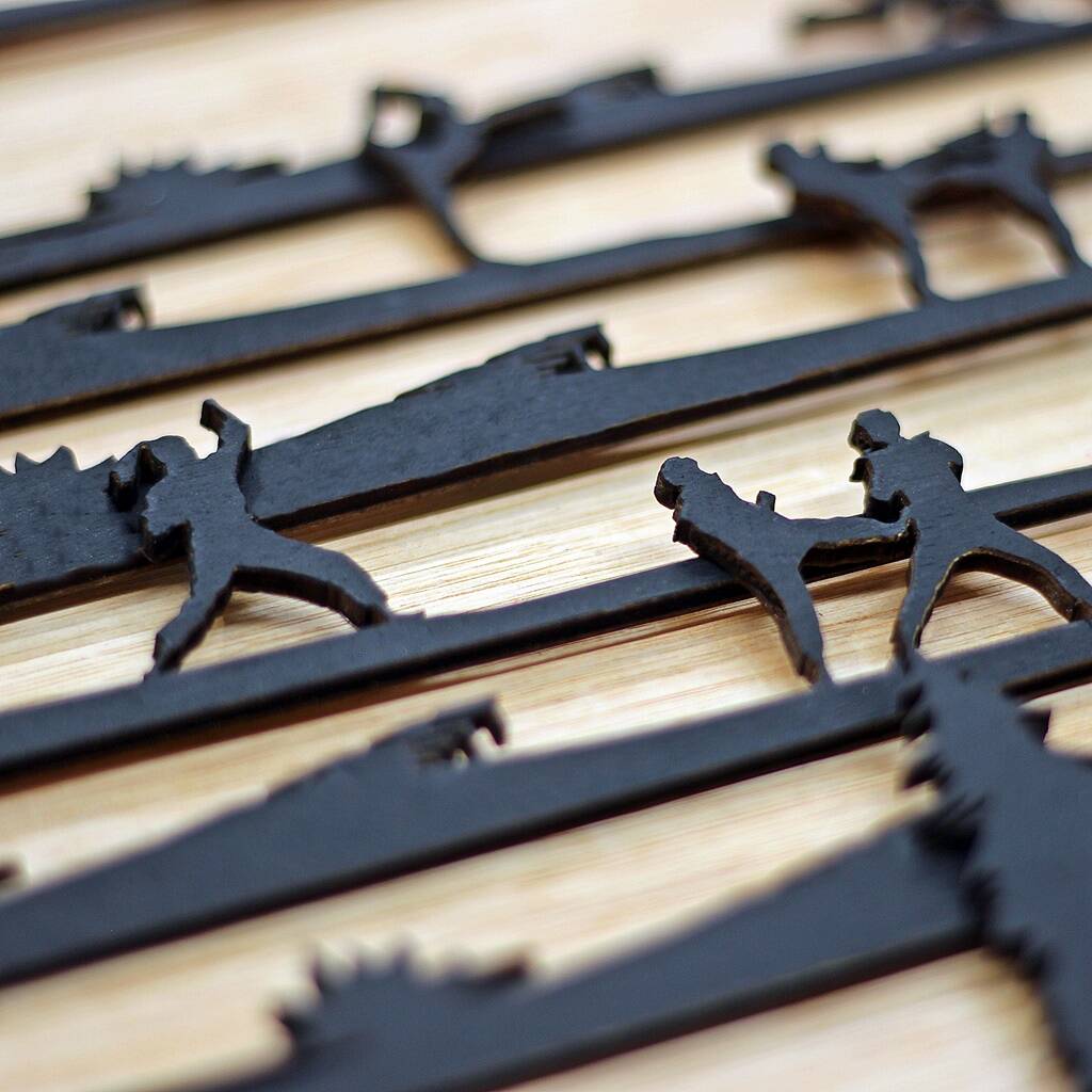 Black metal hooks shaped like people on a wooden surface