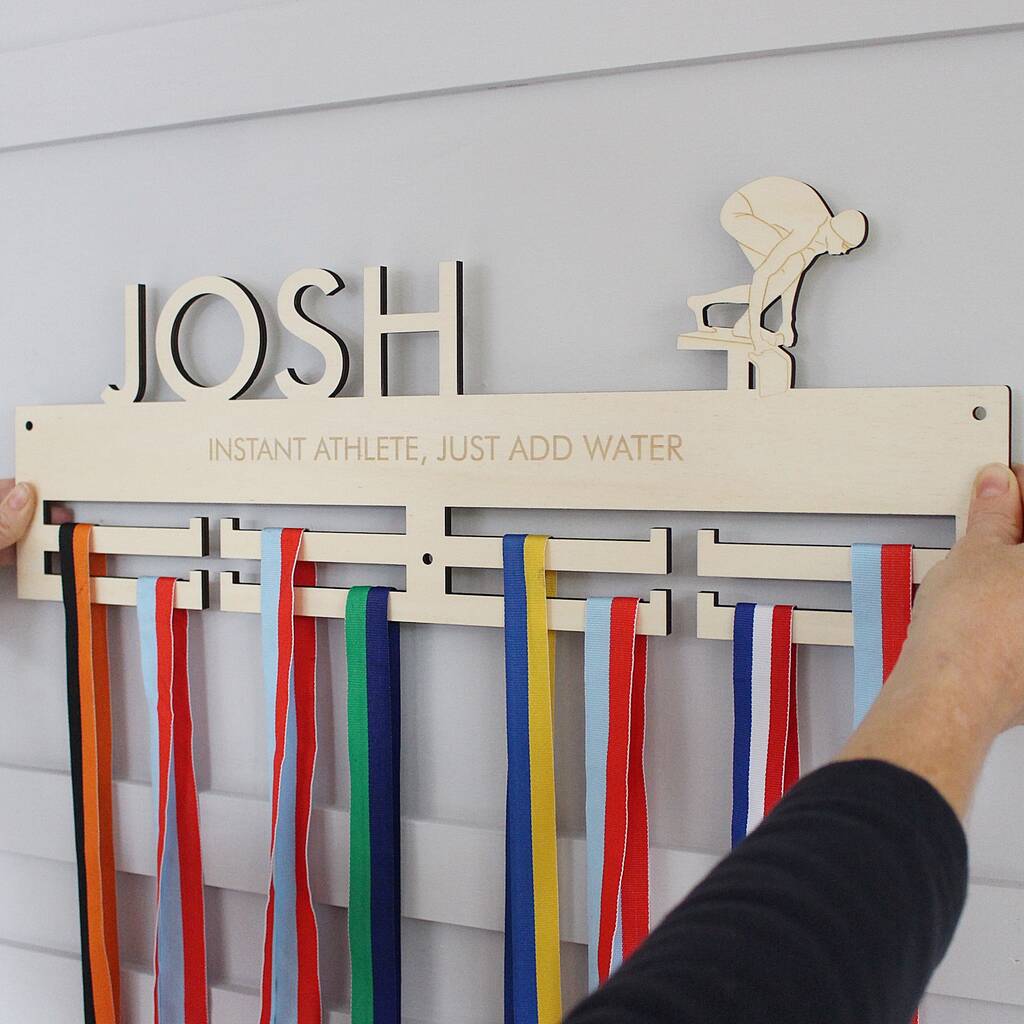 Wooden plaque with ribbons and 'JOSH' engraving on a white wall
