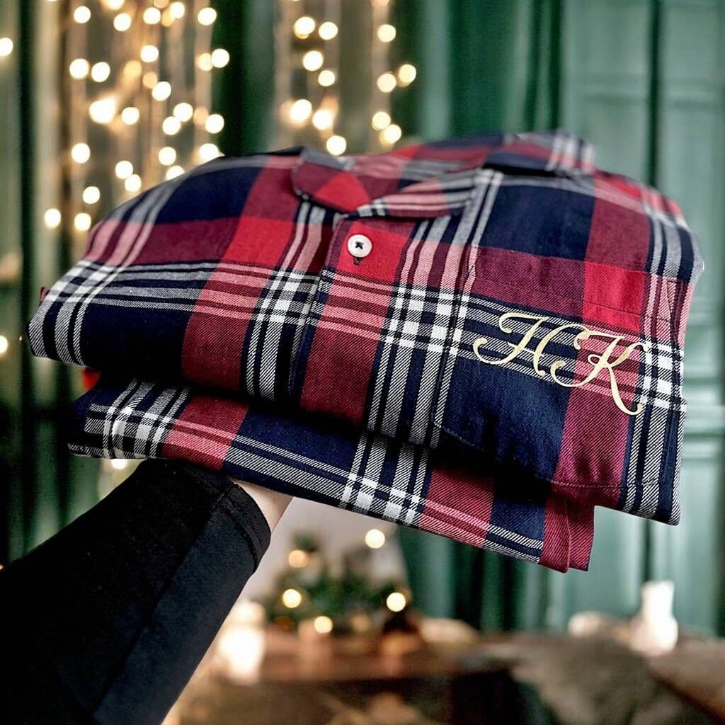 Stack of plaid shirts with initials 'HK' held against a festive background with lights.