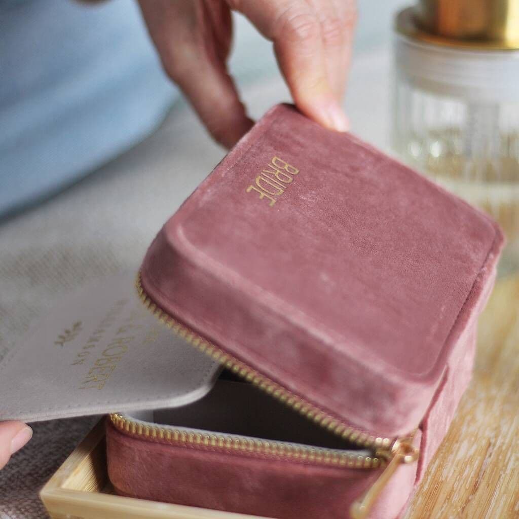 Pink jewelry box with 'Bride' embroidery on a wooden surface