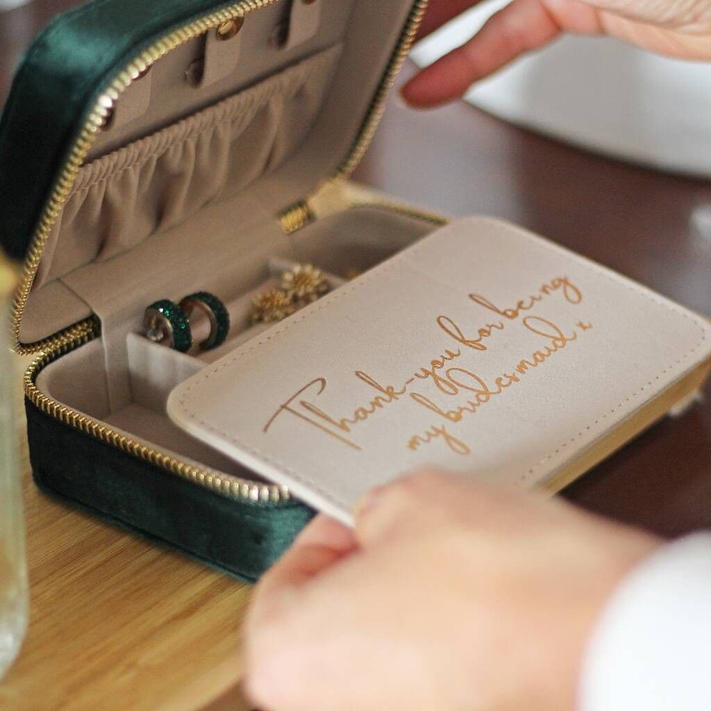 Jewelry box with a card inside, held by a hand on a wooden surface.