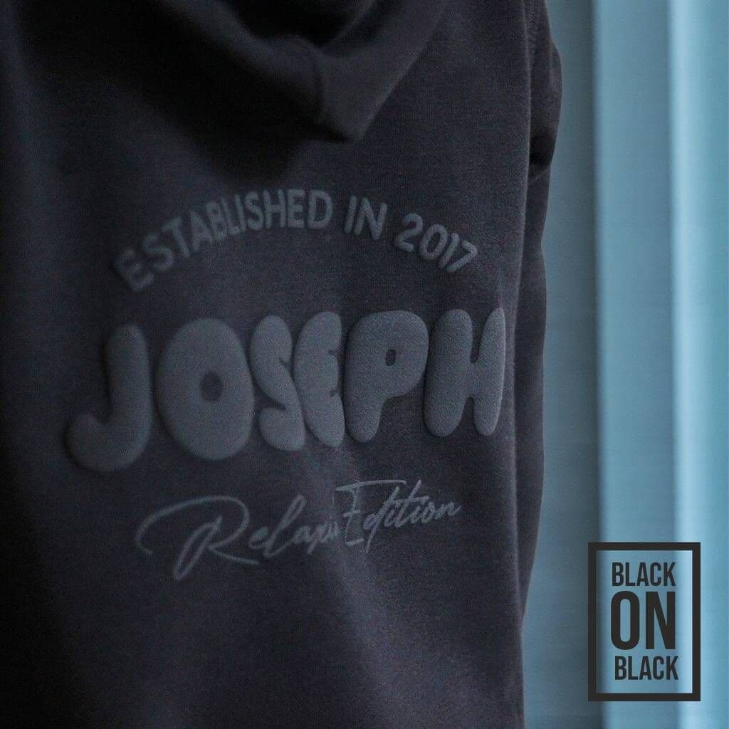 Onesie with 'JOSEPH' puff and text on a dark background