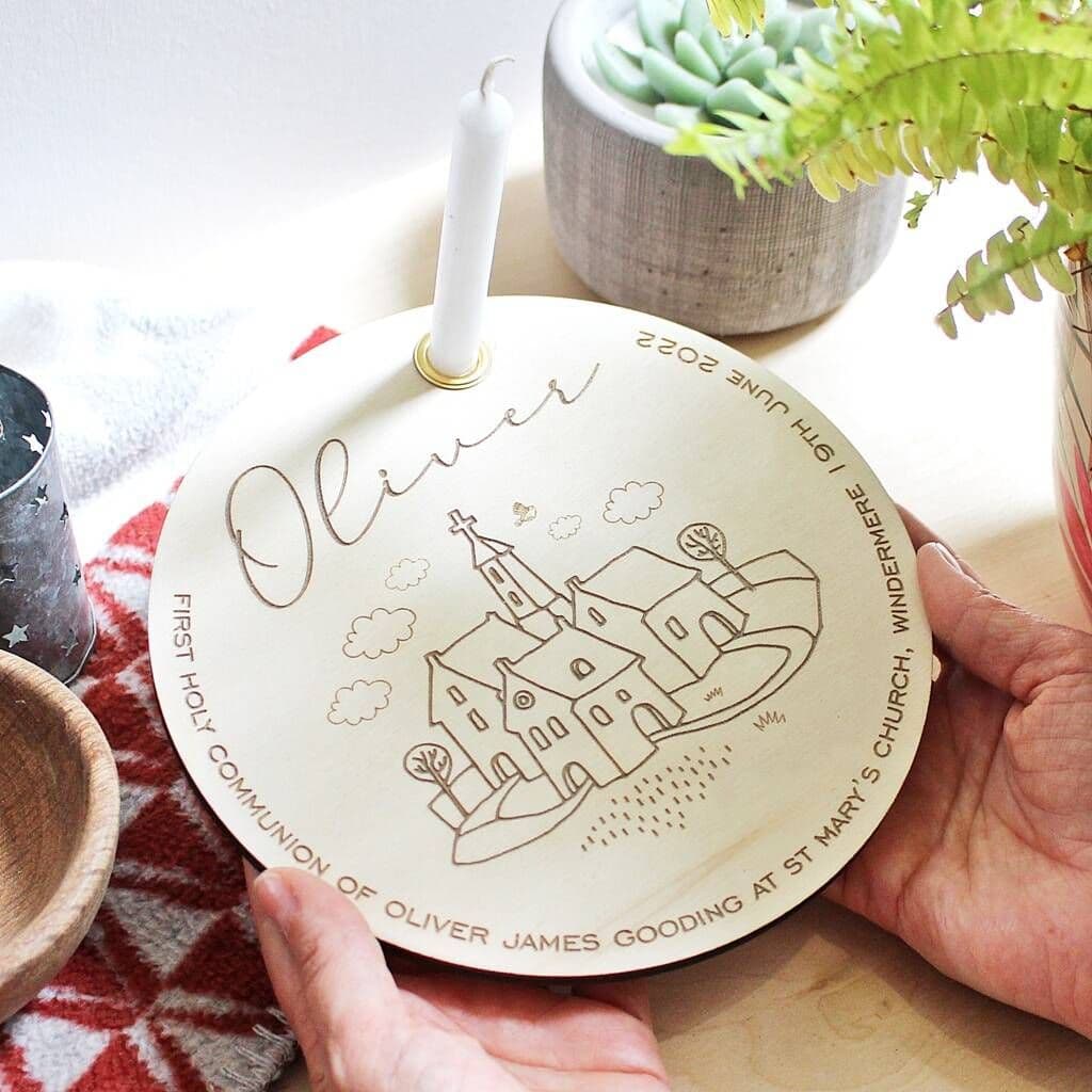 Personalized wooden plate with engraved design and text, held by a hand on a table with plants in the background.