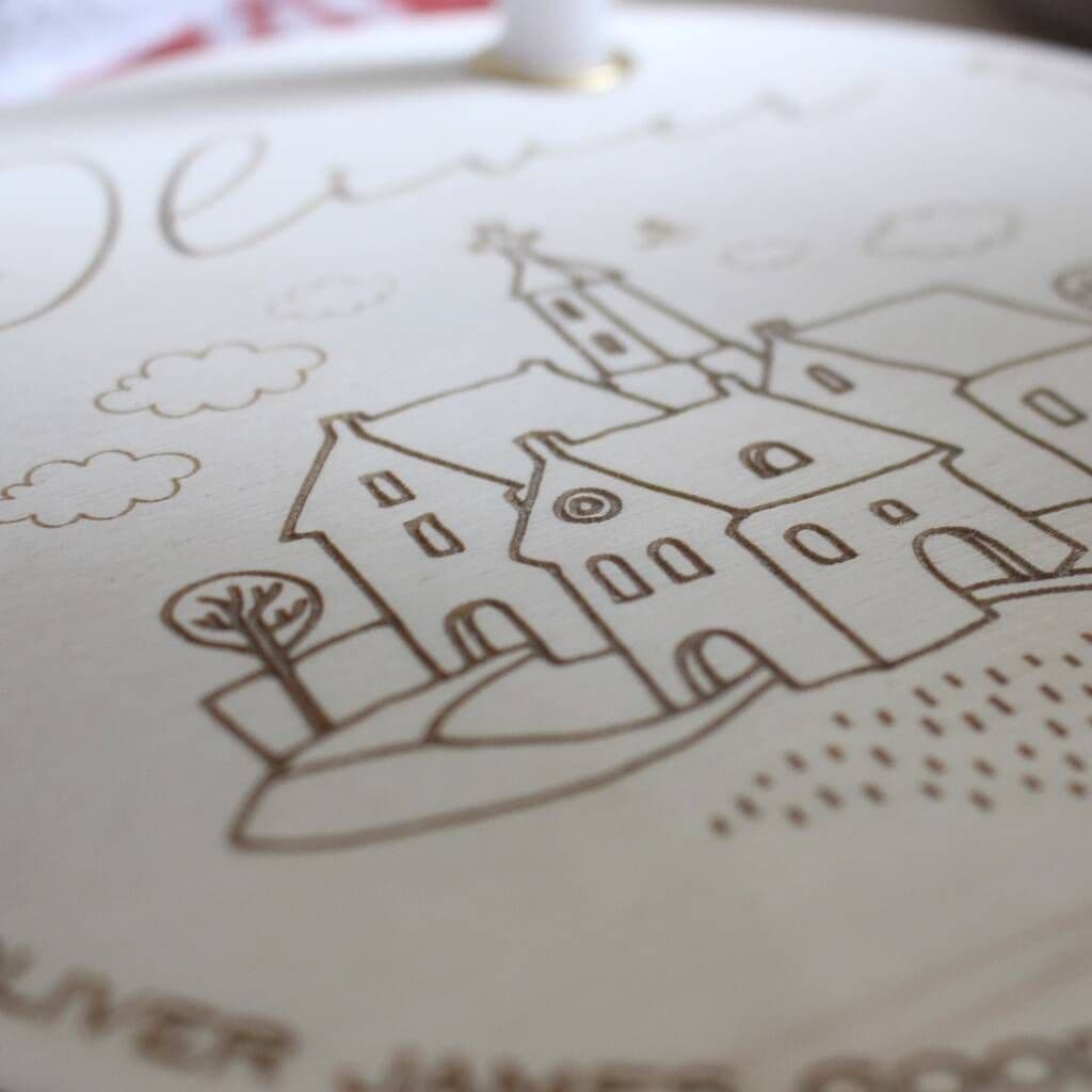 Close-up of a printed design on fabric with houses and trees.