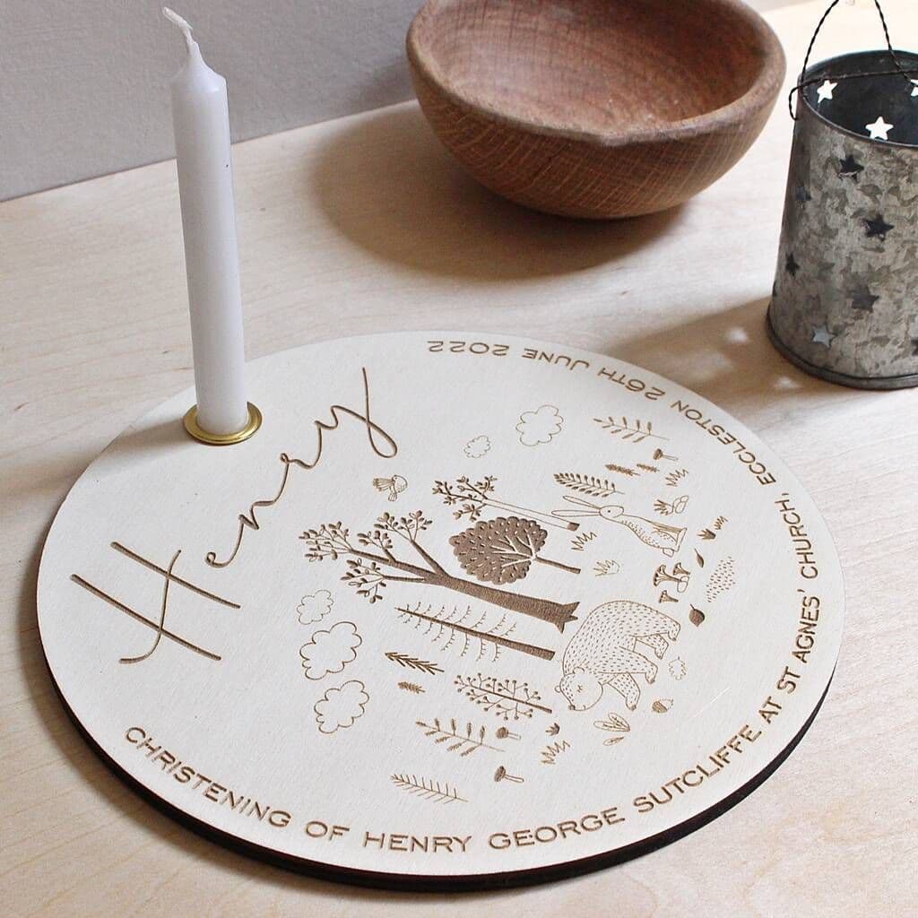 Decorative round plaque with engraved designs and text, featuring a candle on a wooden surface.