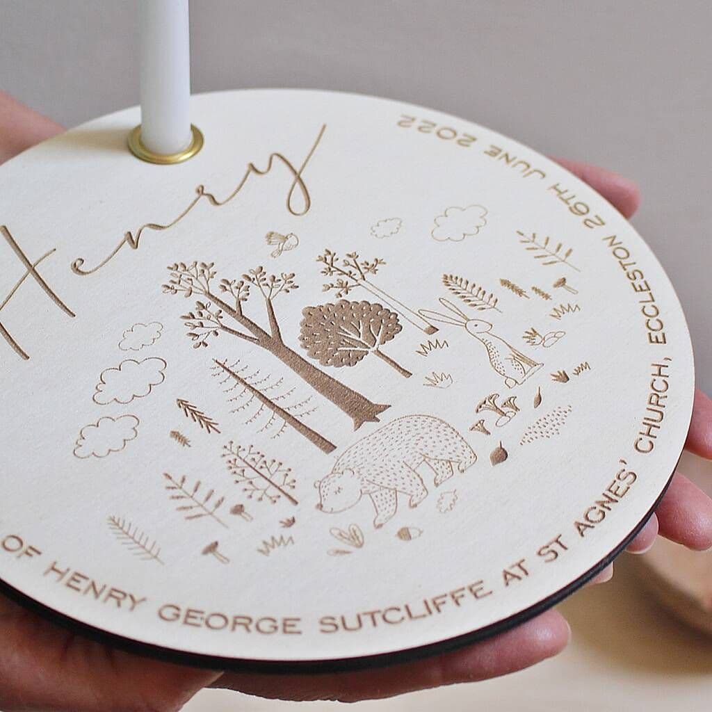 Round engraved object with nature-themed designs and text, held by a hand.