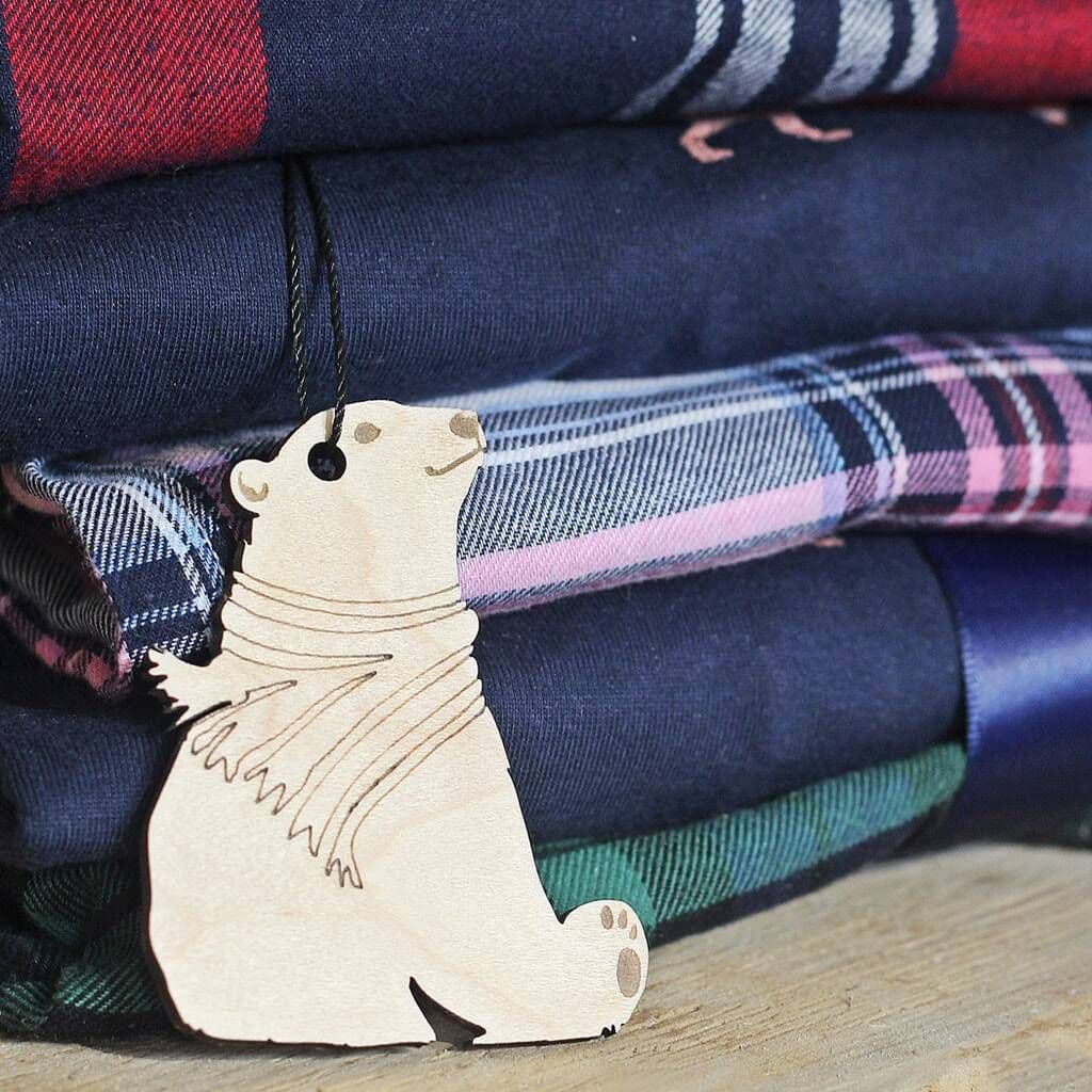 Wooden polar bear ornament hanging on a stack of plaid fabrics.