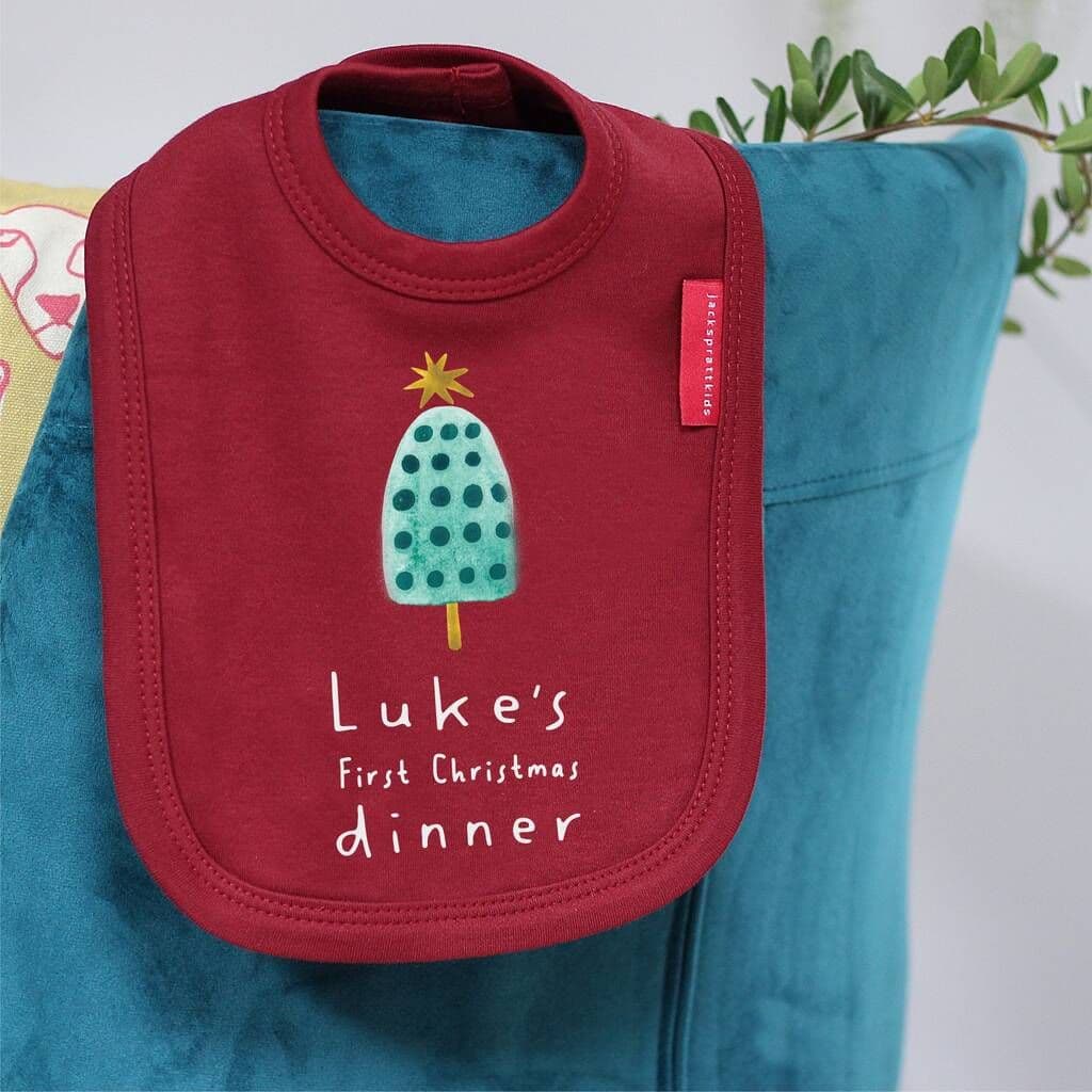 Red bib with a tree design and text on a blue outfit, featuring a brand tag.
