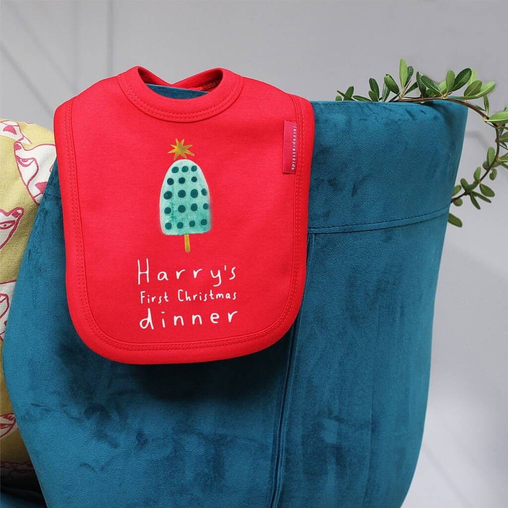 Red bib with 'Harry's First Christmas dinner' text and ice cream design on a blue bag.