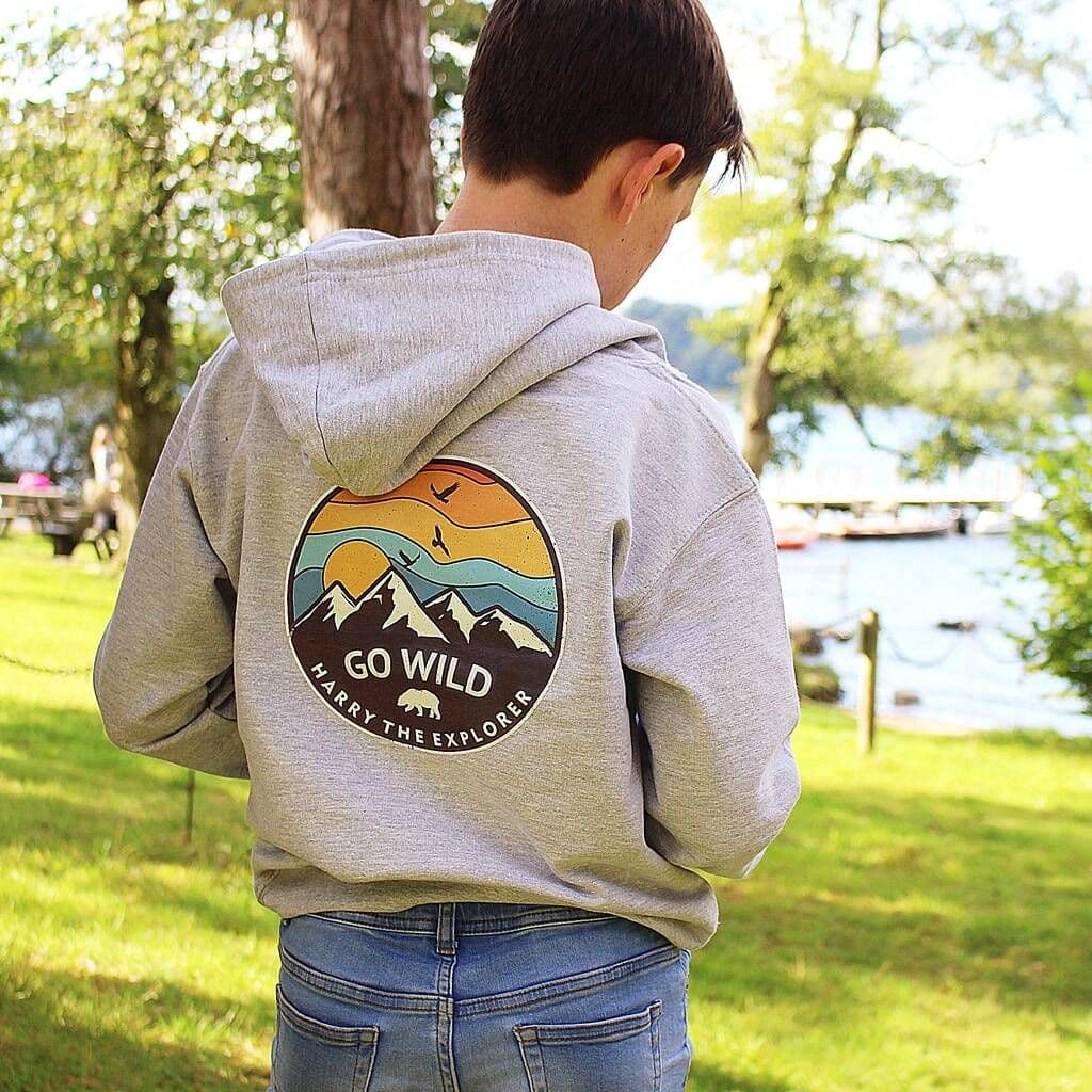 Person wearing a hoodie with 'Go Wild' design in a park setting