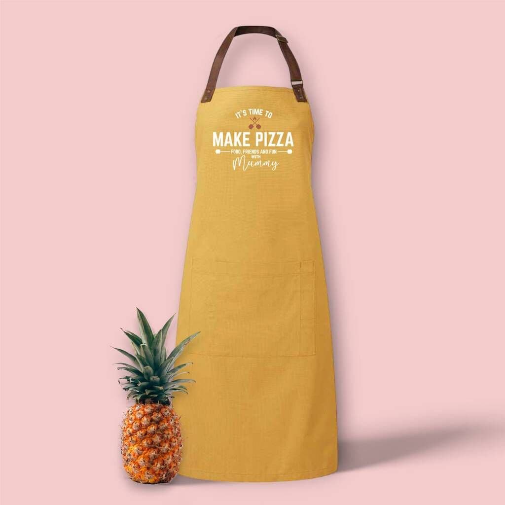 Yellow apron with 'Make Pizza' text next to a pineapple on a pink background