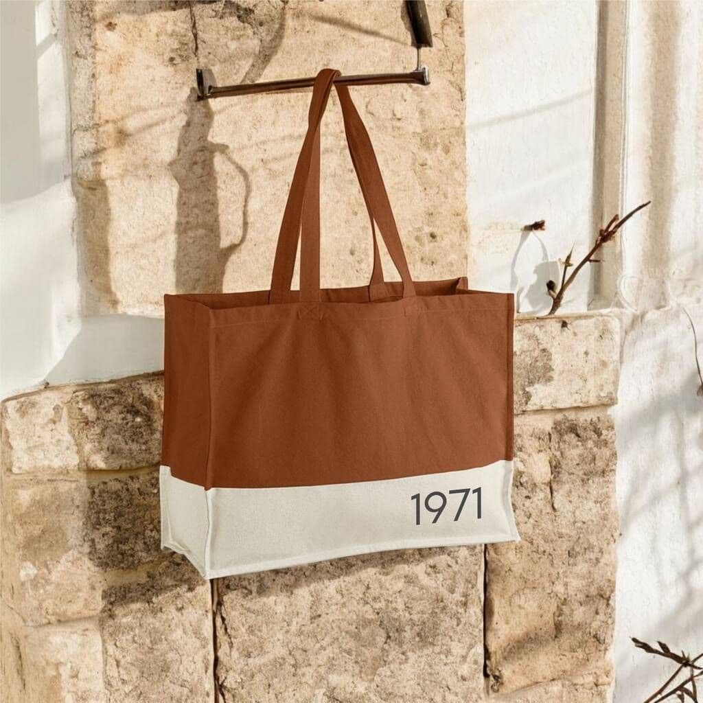 Brown tote bag with '1971' on a stone wall