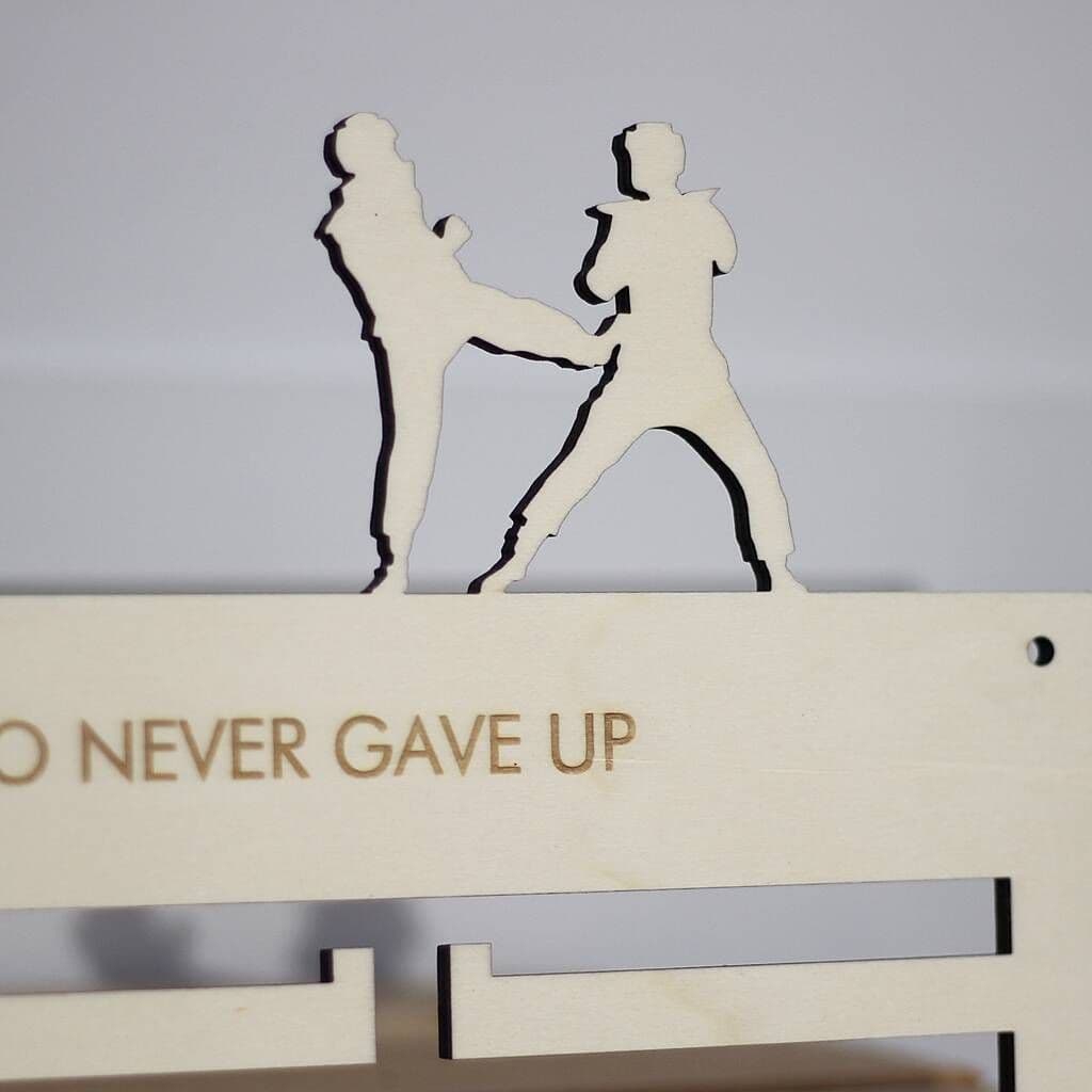 Decorative wall art with silhouettes of a woman and a child, and the text 'NEVER GAVE UP' on a plain background.