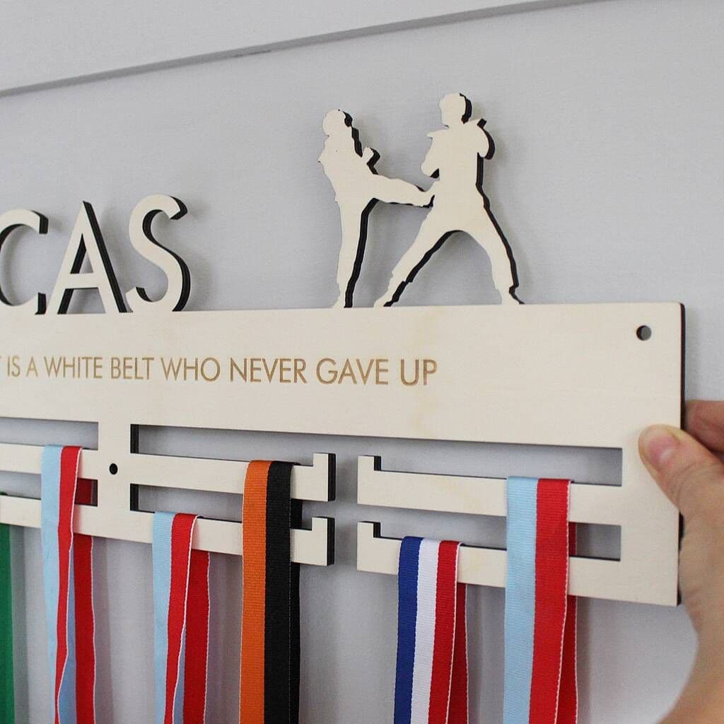 Medal holder with ribbons and motivational quote on a wall