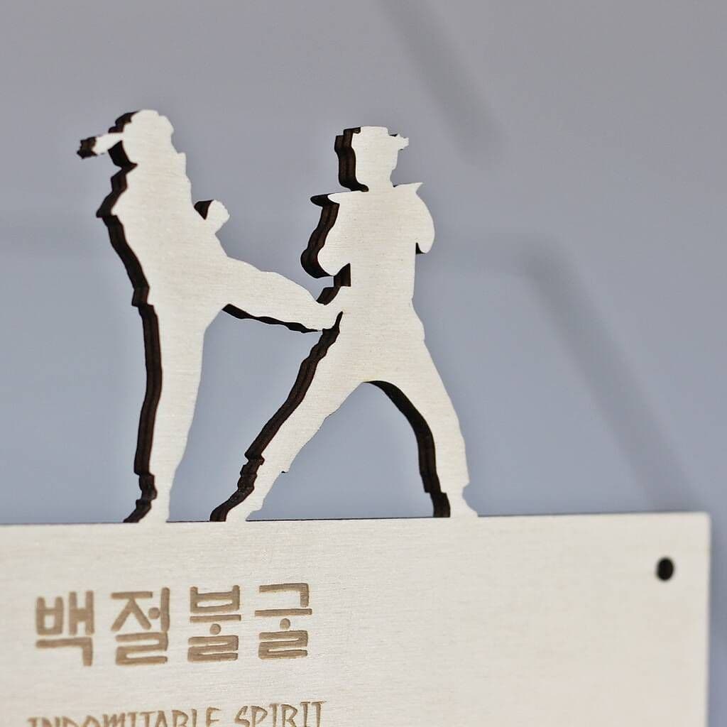 Decorative item with silhouettes of two people and Korean text on a gray background