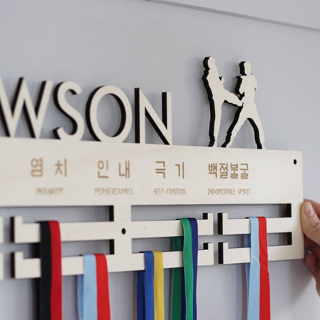 Medal holder with ribbons against a wall with first name Lawson