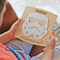 Person holding a wooden cutout of a stormtrooper helmet with 'Hugo' and 'Stormtrooper' text.